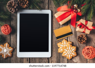 flat lay with digital tablet, credit card, cookies and christmas gifts on wooden background - Powered by Shutterstock