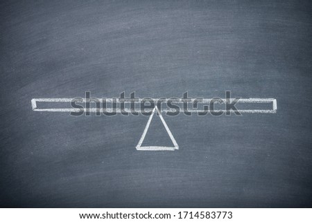 Flat lay of drawing empty seesaw or balance scale in equilibrium on chalkboard or blackboard background with copy space. Concept of decision, comparison and measuring.