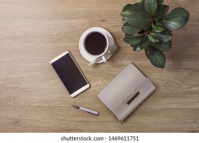 Flat lay empty mobile phone with empty screen, coffee cup on wooden table top.