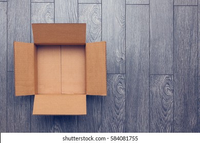 Flat Lay Of Empty Open Cardboard Box On Wooden Surface With Empty Space