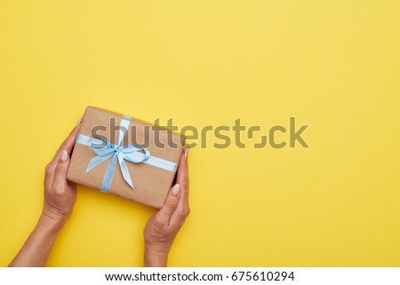 Flat lay of fantastic wrapped present decorated with bow on yellow background
