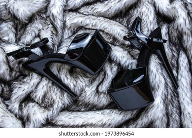 Flat lay female black high-heeled shoes collage on wolf fur background. Female sandals with very high heels.