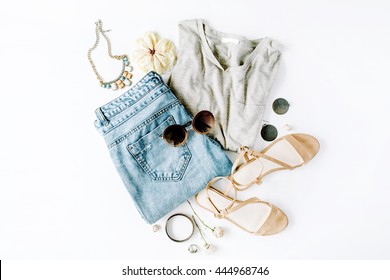 flat lay feminini clothes and accessories collage with shirt, jeans shorts, sunglasses, bracelet, sandals, earrings on white background.