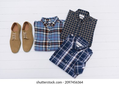 flat lay folded ,checkered or plaid shirt  with white shoes on brown shoes on wooden background

 - Shutterstock ID 2097456364