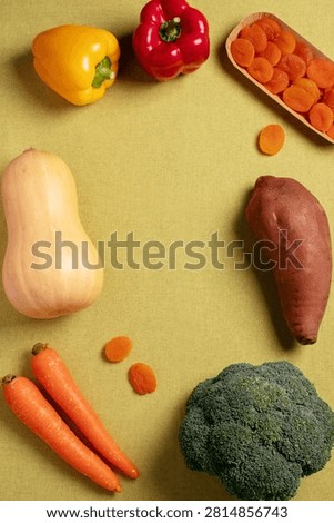 Flat lay frame of beta carotene rich foods including bell peppers, butternut squash, carrots, sweet potato, broccoli and dried apricots, top view