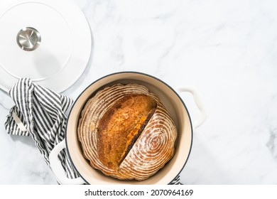 Flat lay. Freshly baked loaf of a wheat sourdough bread with marks from bread proofing basket in enameled cast iron dutch oven. - Shutterstock ID 2070964169