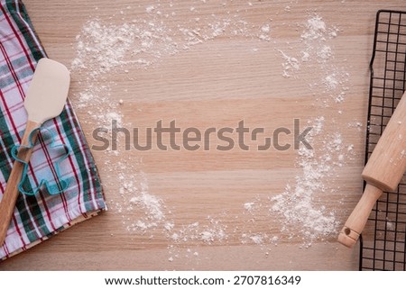 flat lay of gingerbread cookie cutter and christmas towel on cutting board with flour and rolling pin