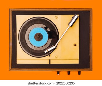 Flat lay gramophone record player from sixties. Turntable for single vinyl on orange background.