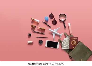 Flat Lay Of Green Leather Woman Shoulder Bag Open Out With Cosmetics, Accessories , Smartphone , Money And Passport On Pink Background