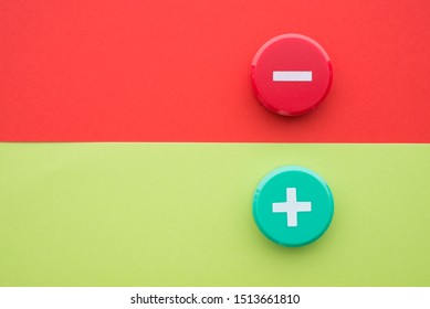 Flat lay of green plus and red minus symbol plastic botton on green and red background with copy space. Concept of difference, opposites plus vs minus or pros vs cons.