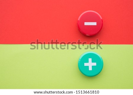Flat lay of green plus and red minus symbol plastic botton on green and red background with copy space. Concept of difference, opposites plus vs minus or pros vs cons.