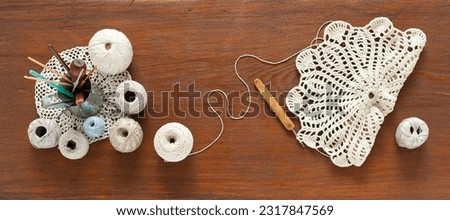 Flat lay of hand crochet lace doily process on wooden background. Set of cotton yarn natural pastel colors and crochet hooks in mug. DIY concept, handmade gifts. Top view, close-up, mock up