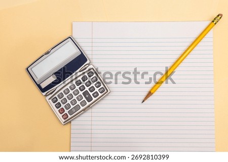 flat lay of a handheld calculator and a sharpened pencil on notebook paper against manila folders