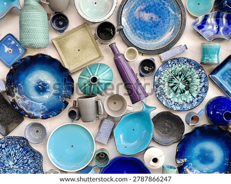 Flat lay of handmade blue ceramic plates and pottery tableware. Artisan craft background for sustainable lifestyle branding. Top view of rustic earthenware dishes and turquoise clay cups. Creative flatlay backdrop for restaurant menus and home decor. Abstract ocean blue glazed pottery collection. Premium artistic background for luxury kitchenware ads and interior magazines.