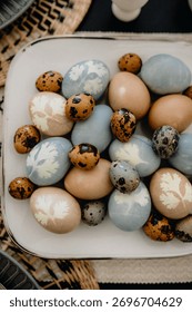 Flat lay of handmade Easter eggs and quail eggs dyed with natural pigments and botanical leaf imprints.
