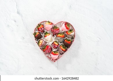 Flat lay. Heart shaped box with assorted chocolate covered strawberries on a white background.