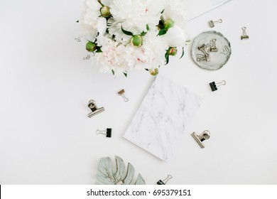 Flat lay home office desk. Woman workspace with white peony flowers bouquet, accessories, marble diary on white background. Top view feminine background.
