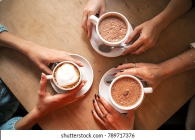 Flat Lay Image From Above: Three Hands Holding Three Cup Of Coffee On A Wooden Table. Cozy, Lifestyle Image