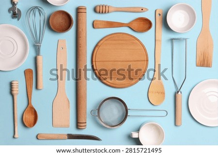 A flat lay image featuring assorted wooden spoons spatulas rollers measuring cups and bowls neatly arranged on a blue backdrop for culinary and home lifestyle photography