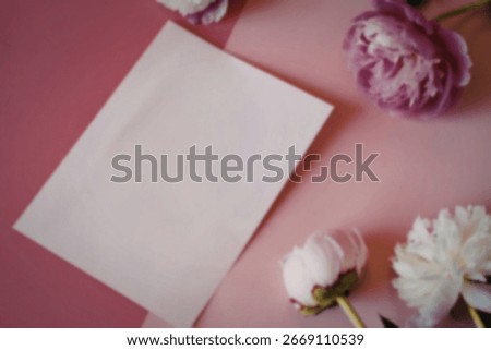 A flat lay image featuring a blank pale pink notecard surrounded by pink and white peonies on a pink background. The scene is minimalist and elegant.