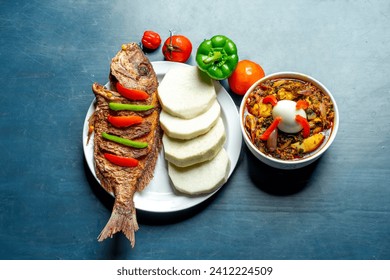 flat lay image of fried fish with ingredients and a sliced of yam arranged on a plate, sauce in a bowl- food concept 