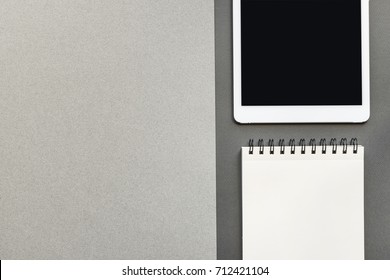 Flat lay image of gray scale blank spaces of neatly arranged cardboard, tablet computer and paper notebook
