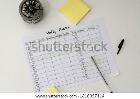 Flat lay image of weekly planner with stationary scattered around. Revision timetable for exams or activity planner.