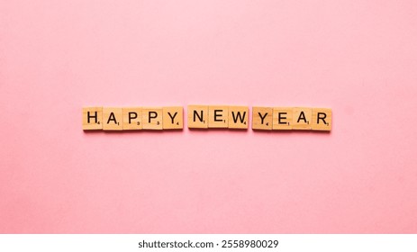 A flat lay image of wooden scrabble tiles spelling out "HAPPY NEW YEAR" on a vibrant pink background - Powered by Shutterstock