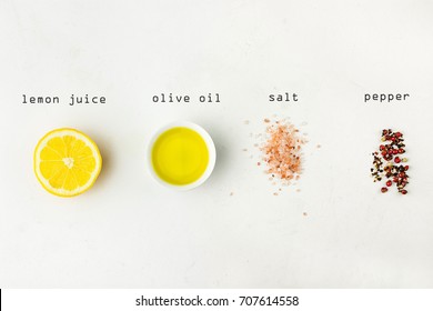 Flat lay of ingredients for vinaigrette sauce. Lemon, olive oil, Himalayan salt red black white pepper on white stone background. Typed lettering. Poster, menu template. Minimalist. - Powered by Shutterstock
