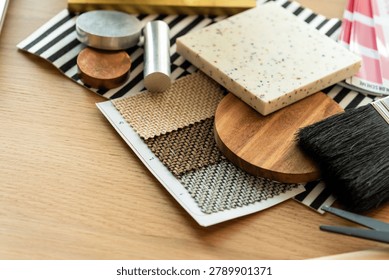 A flat lay of interior design materials including fabric swatches, wood samples, a brush, and a terrazzo tile on a wooden surface.