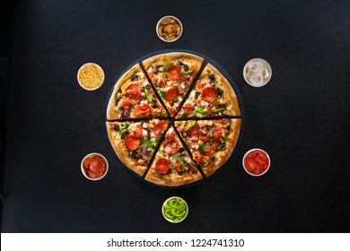 Flat lay of italian pizza and fresh ingredients around on dark surface top view