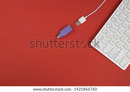 Flat lay of a keyboard with a USB wired connection and a PS2 adapter with copyspace - Red