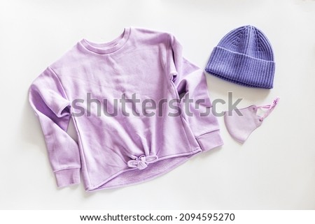Flat lay of knitted hat and Protective face mask on gray concrete nackground. Color of the year 2022 very peri. Trendy colors concept, mockup with copy space