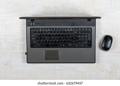 Flat lay lap top with mouse above wooden background.