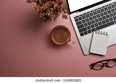 Flat lay, laptop computer, coffee cup, glasses and dry flowers on pink background. Feminine workspace.