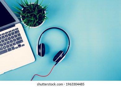 Flat lay of Laptop computer and plant on desk in office, workplace and notebook and potted tree and headphone, workspace and copy space, top view, object with above, nobody, business concept.