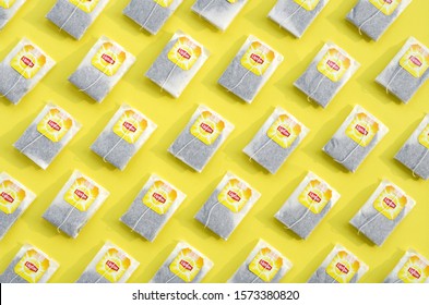 Flat lay of Lipton Yellow Label black tea bags on pastel yellow surface. Lipton is a world famous brand of tea