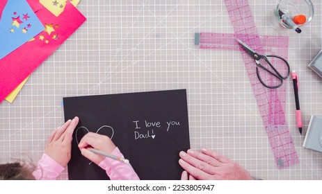 Flat lay. Little girl making a handmade Father's Day card from construction paper. - Powered by Shutterstock