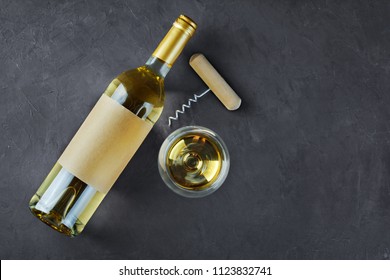 Flat Lay Of Lying White Wine Bottle With Empty Label, Corkscrew And Glass For Tasting On Dark Gray Concrete Background