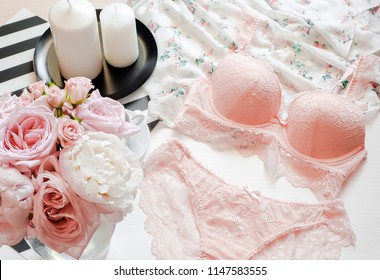 Flat lay, magazines, social media. Top view pink lace lingerie. Beauty blog concept. Woman fashion accessories, underwear, bouquet of roses and pions, parfume, jewelry, coffee on white bed background