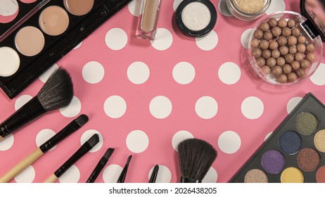 Flat lay of make up and beauty cosmetic products over pink background with white dots
