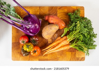 Flat lay of mixed raw vegetables on large wooden chopping board in kitchen. Perfect healthy food option for breakfast, lunch or dinner. Carrots, tomatoes, potato and sweet potato - Powered by Shutterstock