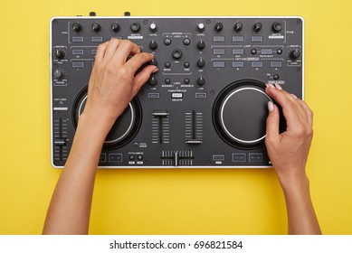 Flat Lay Of Mixing Board On Yellow Background. View Of Hands Of Woman Using Electronic Device, Mid Shot