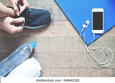 Flat lay of mobile phone with earphone and sport equipment on wood background. Woman in black sneaker with sport equipment, top view - Powered by Shutterstock