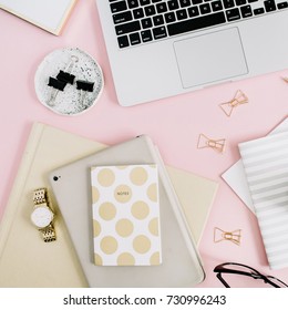 Flat lay modern workspace with laptop, notebook and stationery on pastel pink background. Top view. Golden style lifestyle concept.