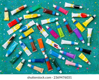 Flat lay multi colored paint tubes on abstract green background 
