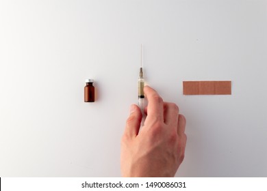 Flat lay of needle, band aid and vial of medicine. Hand reaching for needle. Flu - Shutterstock ID 1490086031