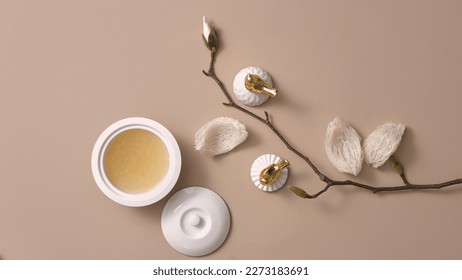Flat lay of bird’s nest soup contained in a porcelain bowl, decorated with edible bird’s nest and a flower branch. Bird’s nest is a expensive and high-class dessert