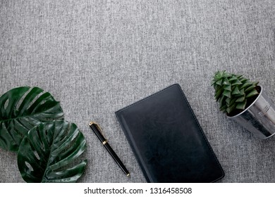 flat lay note book on gray background, tropical leaves and succulent, creative ideas and concept 