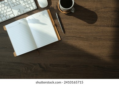 Flat lay notebook, coffee cup and potted plant on wood office desk.